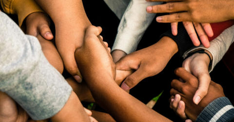A close-up of a bunch of diverse people clasping hands together